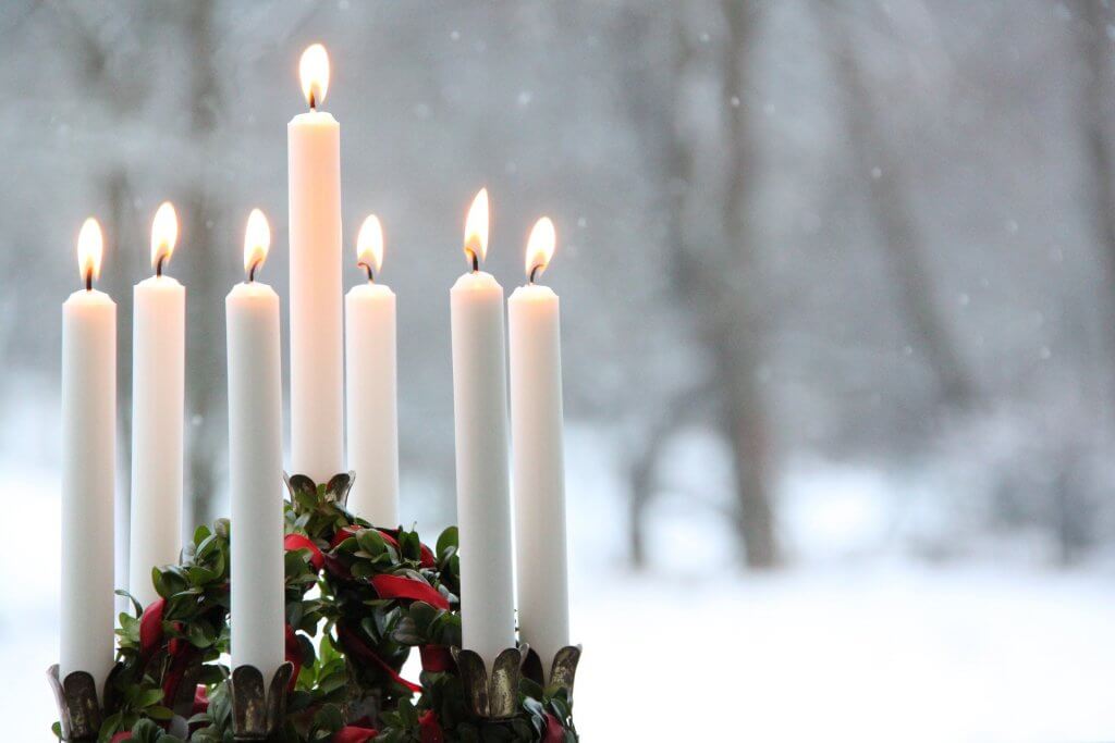 A wreath of lit candles burns in a snowy landscape