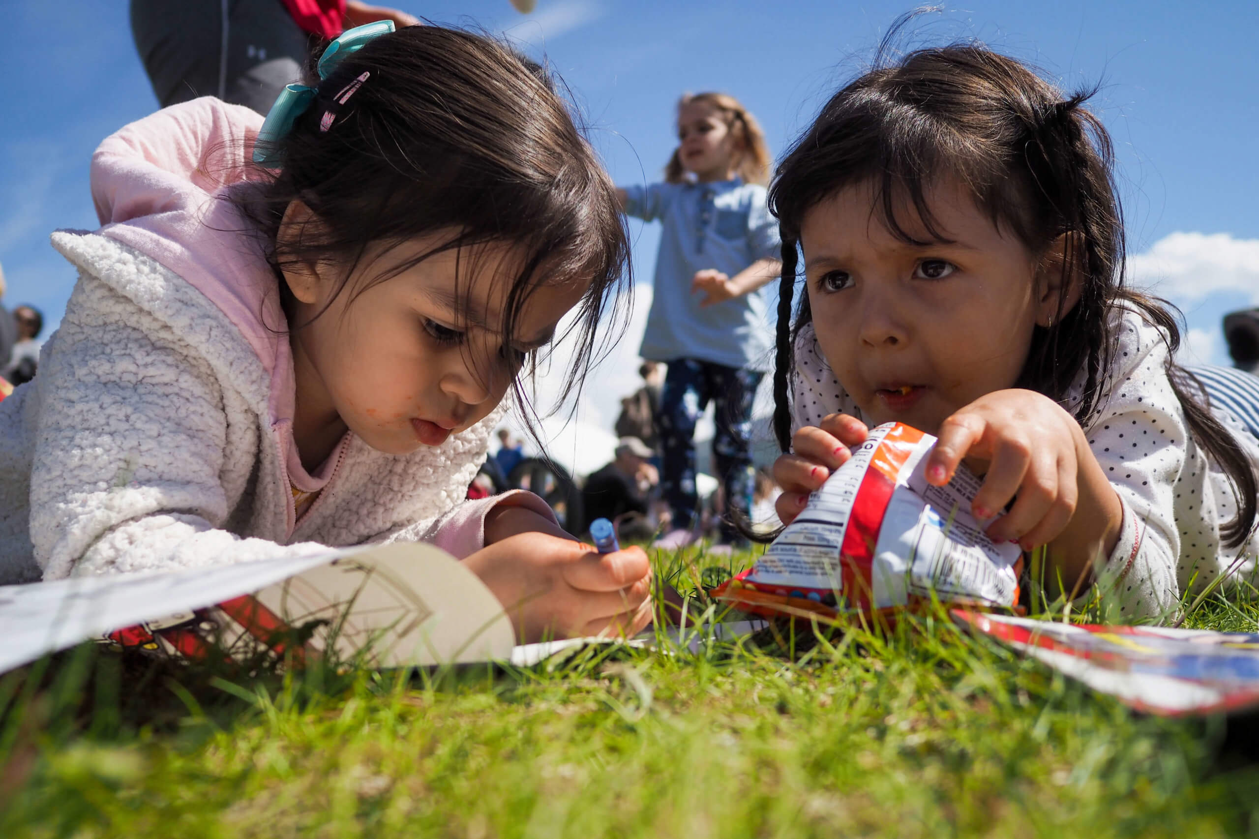 Two girls eating chips and colouring