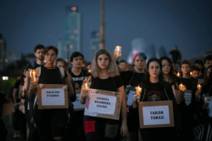 Extinction Rebellion activists dressed in black carry candles and the names of murdered activists in the global south.