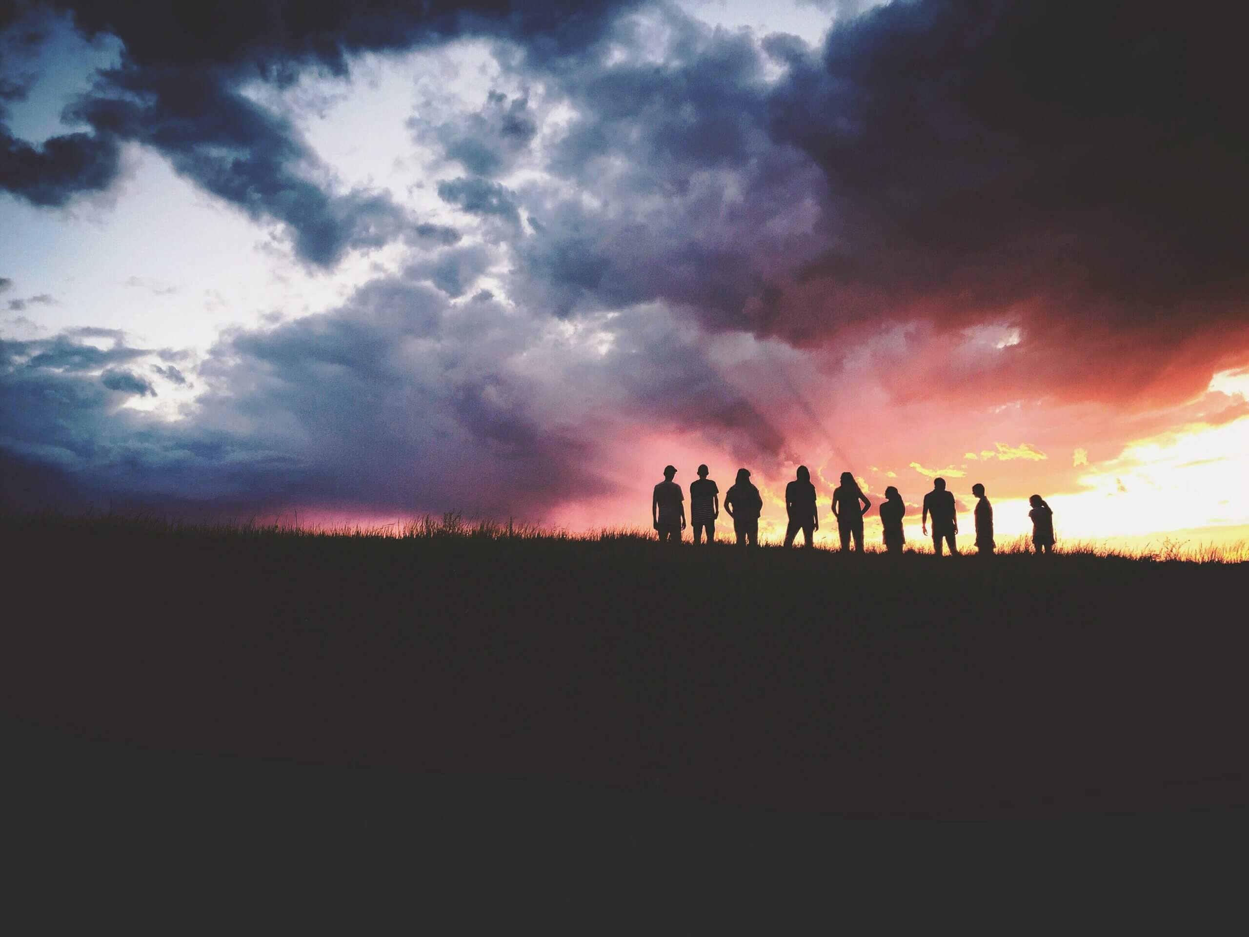 Silhouette of 9 people against a dramatic sunset. Photo by Hudson Hintze on Unsplash