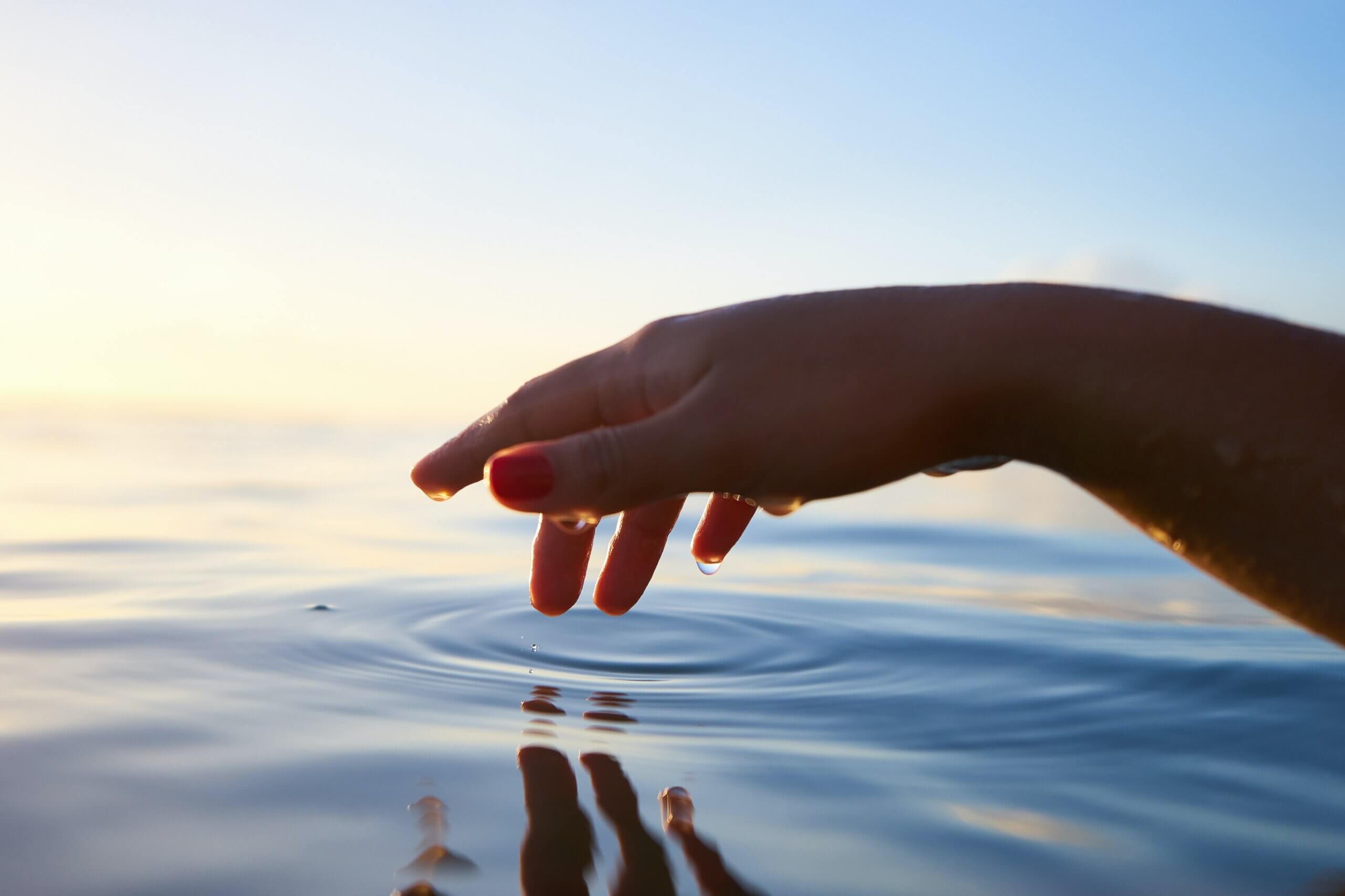 a hand dips into clear water