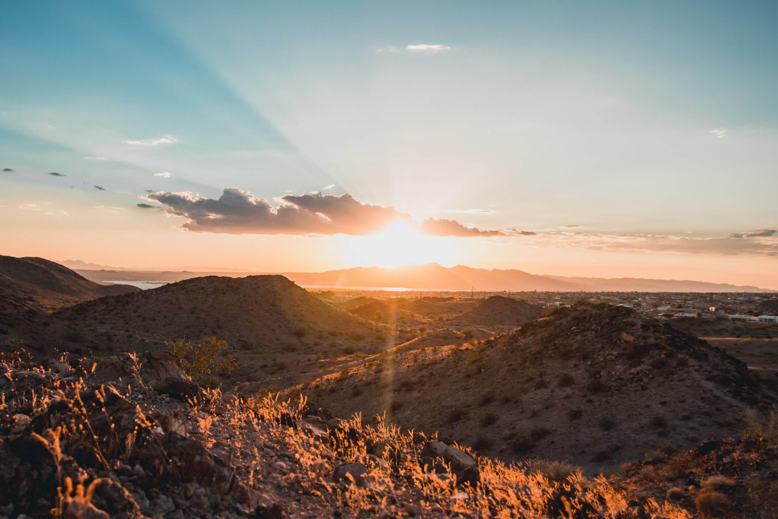 sunset over low mountains with a desert city in the distance