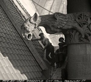 Workers replacing Old City Hall’s roof pose by a gargoyle overlooking Terauly St (now Bay), 1920.