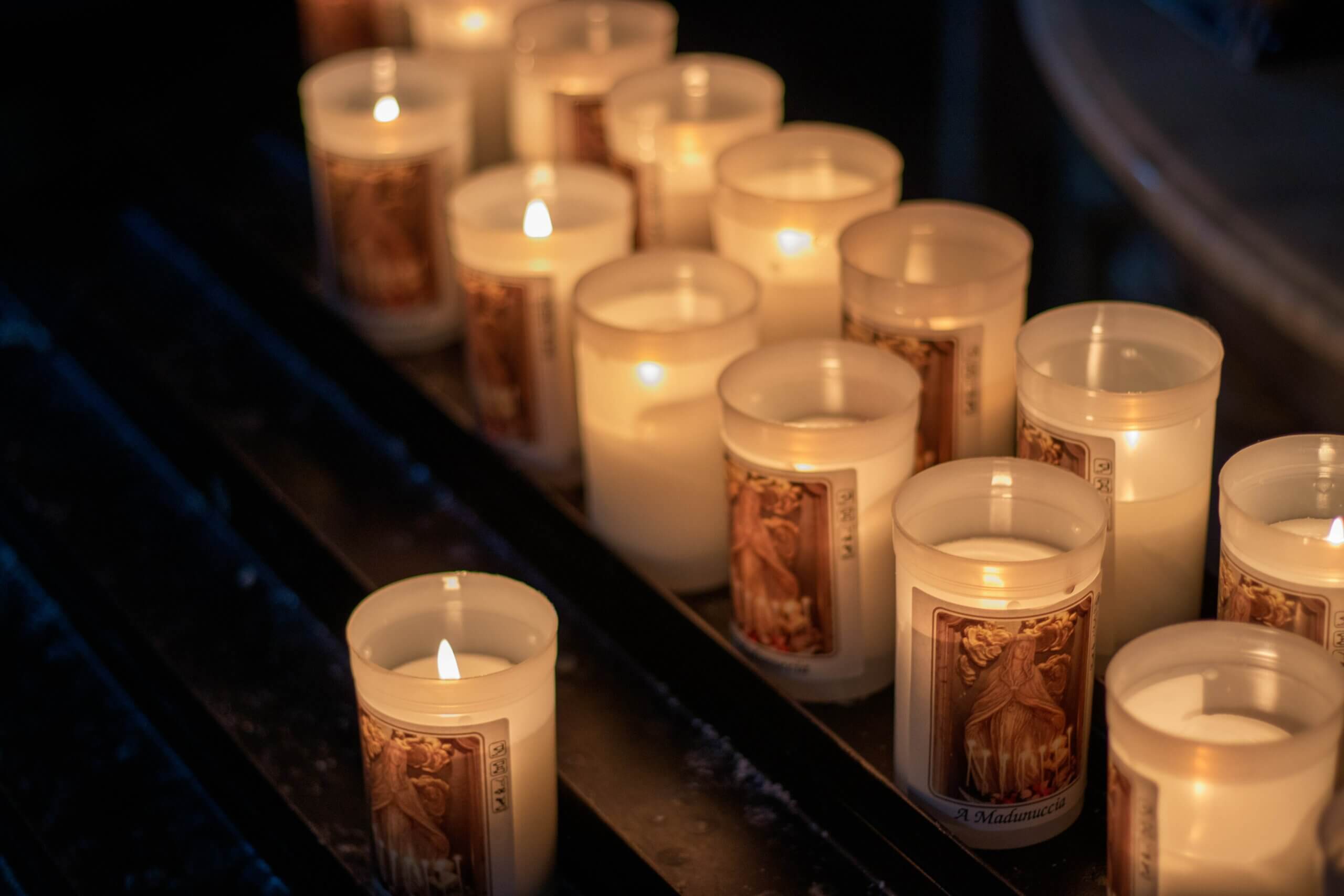 two rows of votive candles burning in the dark