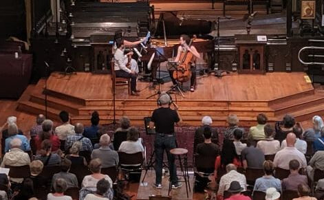 A string quartet set up on the stage at Holy Trinity with an audience gathered.